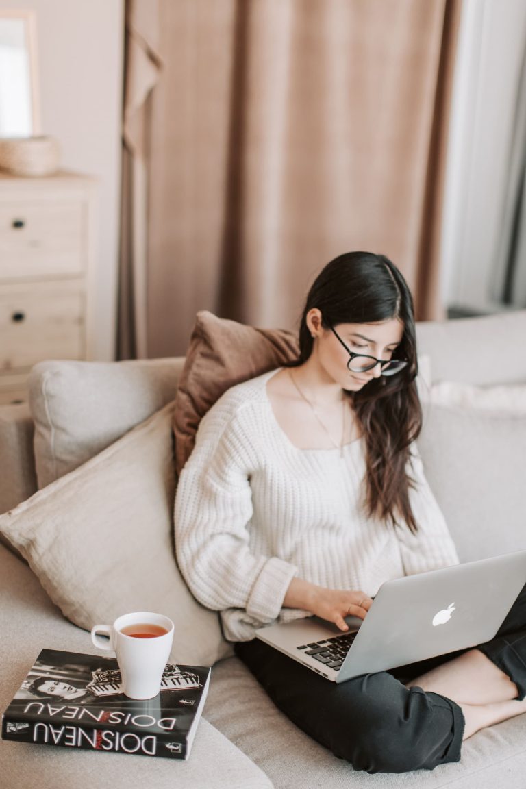 Mujer joven relajada en el sofá durante una sesión de terapia emocional online, y tomando un café en un entorno de calma y bienestar.